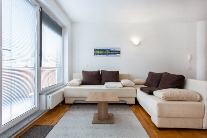 Svetel dnevni prostor z velikimi okni ter kavčem.